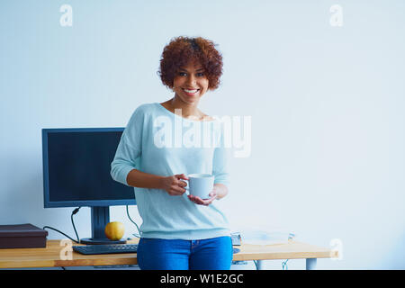 Happy Programmiererin im Büro mit Tasse Kaffee Stockfoto