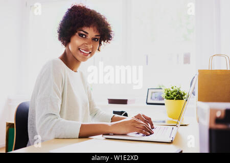 Gerne afrikanische Frau, die von zu Hause aus arbeiten am Laptop Stockfoto
