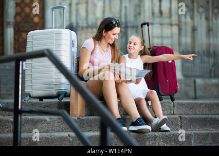 Porträt von Frauen mit Mädchen sitzen auf alten Kathedrale Schritte suchen Karte Stockfoto