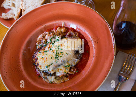 Teil der leckeren Moussaka mit gehackten Schnittlauch auf Keramik Teller dekoriert Stockfoto