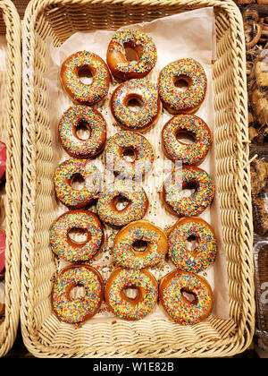 Süße Krapfen mit Streuseln, verglast und iced Gebäck in Korb in Bäckerei, Ansicht von oben Stockfoto