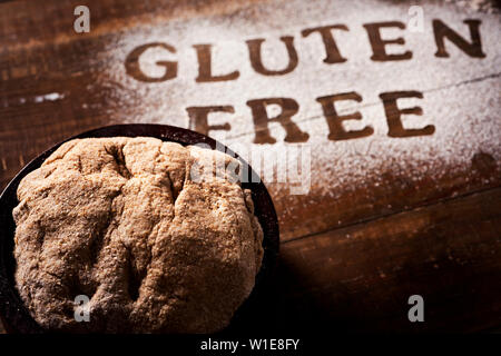 Nahaufnahme von einem Stück Teig auf einem Holztisch mit einem Glutenfreies Mehl, wo Sie den Text Glutenfrei lesen können Stockfoto