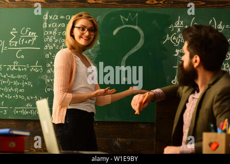 Moderne Lehrer hipster Schreiben auf große Tafel mit mathematischen Formel, Lehrer Schüler respektiert, Lächelnd erwachsene Schüler während der Pause im Klassenzimmer interi Stockfoto