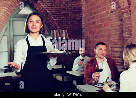 Positive weibliche Kellner die Gäste zu Land Restaurant und lächelnd Stockfoto