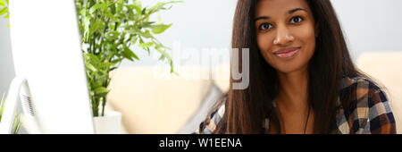 Schwarz lächelnde Frau sitzt am Arbeitsplatz schriftlich etwas Stockfoto