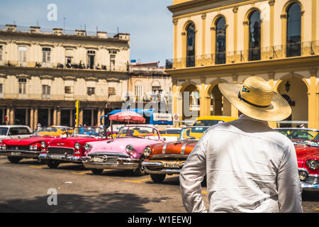 Kubanische Mann mit Blick auf die bunten alten amerikanischen Taxi Autos in Havanna, La Habana, Kuba, Karibik, Karibik Mittelamerika geparkt Stockfoto