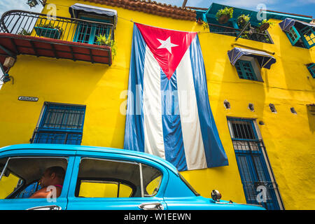Alte amerikanische Oldtimer und riesige kubanische Flagge auf gelbes Gebäude in Havanna, La Habana (Havanna), Kuba, Karibik, Karibik, Zentral- und Lateinamerika Stockfoto
