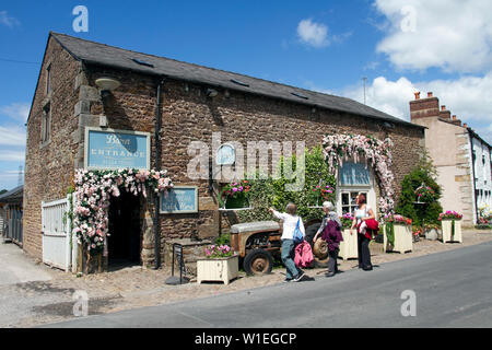 Ein steinernes Touristengeschäft am Straßenrand in Scorton, Lancaster. Vereinigtes Königreich Wetter Juli, 2019. Die Sonne bricht im ländlichen Lancashire über den floralen Darstellungen dekorierter Anwesen im ländlichen Dorf durch. Eine ehemalige Farm und historische Scheune am Straßenrand, die in ein Café & Restaurant umgewandelt wurde. Stockfoto