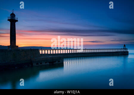 Sonnenuntergang Abendrot über Whitby West Pier und Leuchtturm, die Küste von North Yorkshire, Yorkshire, England, Vereinigtes Königreich, Europa Stockfoto