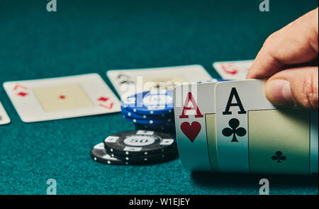 Close-up von zwei Asse in der Hand auf dem Grün spiel Matte auf der rechten Seite des Bildes statt Raum für Bearbeitung, andere Karten und poker chips zu verlassen werden Stockfoto