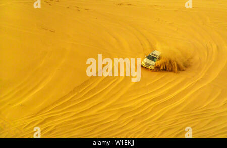 Desert Safari Abenteuer im 4x4 Fahrzeug bashing Seite durch die Dünen der Wüste bei Sonnenuntergang in Katar und Saudi-Arabien, Katar, Naher Osten zu Seite Stockfoto