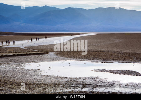 Seitenansicht von Menschen, die über einen Pfad in Badwater Basin, Endorheic Basin, Death Valley National Park, Inyo, Kalifornien, USA gehen Stockfoto