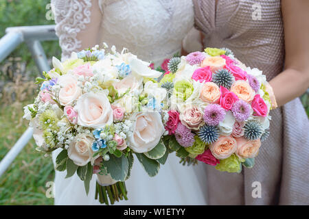 Braut und trauzeugin oder Brautjungfer mit großen, bunten und anspruchsvollen Wedding Bouquets, Kaukasischen jungen Frauen holding Blumenarrangements Stockfoto