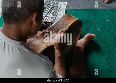 Eine Gitarre Handwerker schnitzen eine klassische Gitarren aus Holz, mit balinesischen Muster, in einem hölzernen Gitarren Workshop an Guwang Dorf, Gianyar, Bali Stockfoto