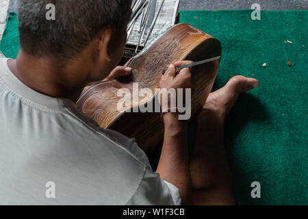 Eine Gitarre Handwerker schnitzen eine klassische Gitarren aus Holz, mit balinesischen Muster, in einem hölzernen Gitarren Workshop an Guwang Dorf, Gianyar, Bali Stockfoto