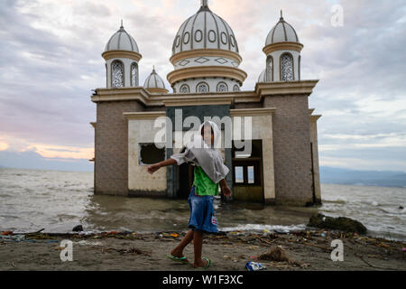 Ein Kind spielt vor den Ruinen einer Moschee, die nach dem Erdbeben und Tsunami am 28. September 2018 in Lere, Palu, Zentral-sulawesi zerstört wurde. Stockfoto