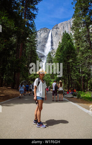 Touristenfrau mit Hut und Schatten posiert mit Yosemite Falls aus dem Yosemite Valley im Yosemite National Park, Kalifornien, USA Stockfoto