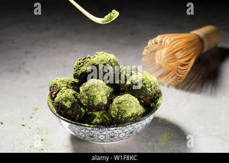 Rohe Energie Kugeln mit Matcha Tee Pulver auf grauem Marmor Hintergrund. Bild horizontal, Vorderansicht. Veganes Dessert Stockfoto