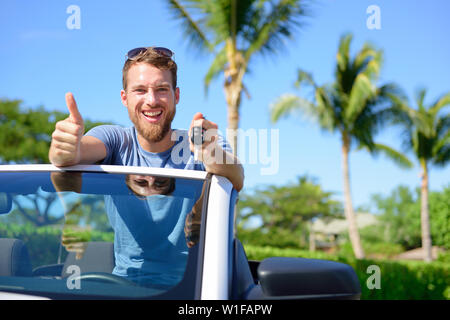 Autofahrer, die Tasten und Daumen hoch zufrieden. Junger Mann mit dem Schlüssel für neue Leasing Cabrio. Mietwagen oder Führerschein Konzept mit männlichen fahren Cabrio auf Road Trip. Stockfoto