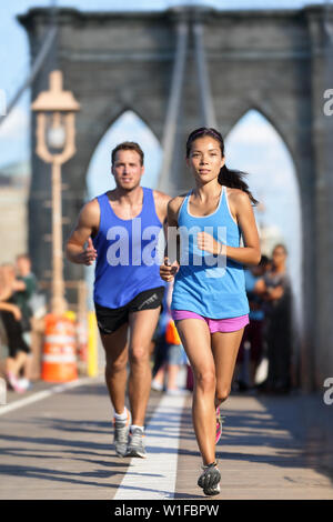 New York Läufer Lauftraining auf der Brooklyn Bridge NEW YORK CITY während der Stoßzeiten voll mit Touristen. Passen junge Paar ihre Workout Routine zu tun an einem Sommertag. Stockfoto