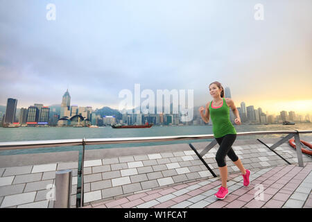 Sport Frau Läufer in Hong Kong Skyline läuft. Asiatische chinesische fitness Sportler joggen training Leben gesunder Lebensstil auf Tsim Sha Tsui Promenade und Avenue der Stars in den Victoria Harbour und Kowloon. Stockfoto