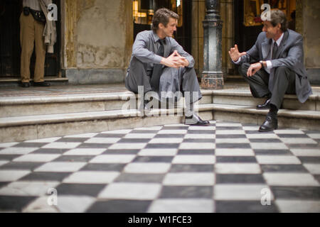 Mitte - Erwachsene business Mann in einem Gespräch mit einem Kollegen, während Sitzen auf einem Schritt in einem Foyer. Stockfoto