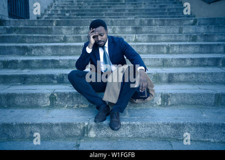 Junge feuerte African American Business Mann in Depressionen weinend sitzen auf dem Boden Straße Treppe leiden emotionalen Schmerz, Traurigkeit in Grunge lightin verloren Stockfoto