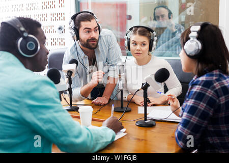 Positive männliche und weibliche Radio hosts Gast Interviews in Rundfunk station Stockfoto