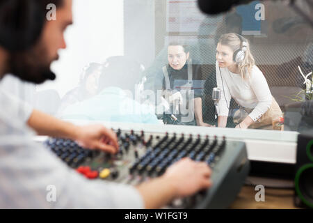 Moderatoren und Gäste in Rundfunk station Hosting live Radio Show. Der Ausblick vom Zimmer wo Audio Engineer controlling Sound on air Stockfoto