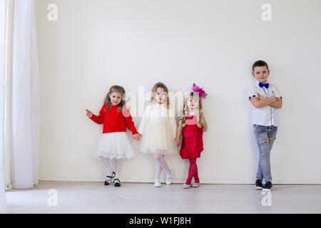 Jungen und drei kleine Mädchen stand auf der weißen Wand Stockfoto