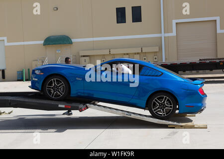 Ein Mann rücken eine neue helle blaue 2019 Ford Mustang GT aus einen Abschleppwagen nach Auslieferung an seinen neuen Eigentümer in Palm City, Florida, USA. Stockfoto