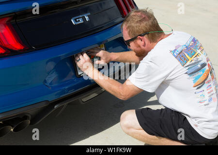 Ein Mann legt eine staatliche Lizenz Platte bei der Lieferung eines neuen Blue 2019 Ford Mustang GT an seinen Besitzer in Palm City, Florida, USA. Stockfoto