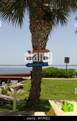 Schilder auf einem Palm Tree außerhalb der trendigen Pelican Cafe in Stuart, Florida, Liste der Kilometerstand zu entfernten Strände. Stockfoto