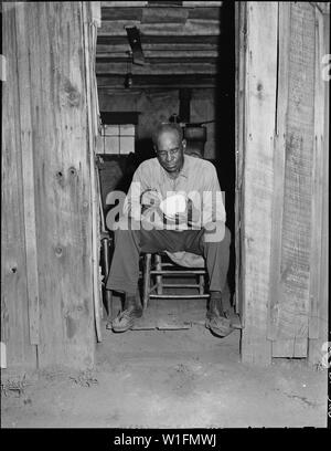 Joshua Spradley, Bergmann, im Eingang seiner zwei Zimmer in der garage Haus saß. Er zahlt $ 10,60 pro Monat mieten, inkl. Strom. Mullens Smokeless Coal Company, Mullens Mine, Harmco, Wyoming County, West Virginia. Stockfoto