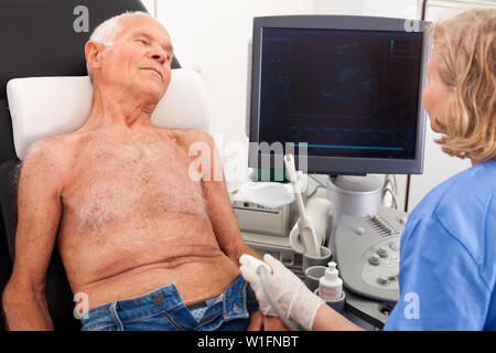 Freundlich lächelnd weibliche Techniker Diagnose von männlichen Patienten mit modernen Ultraschallgerät im privaten Klinik Stockfoto