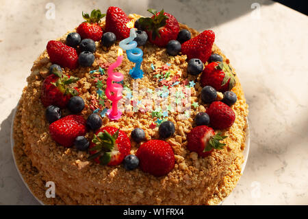 Party Food und festliche Konzept. Hausgemachten Kuchen zum Geburtstag mit Kerzen geschmückt, frische Heidelbeeren, Erdbeeren. Zwei Jahre alt. Stockfoto