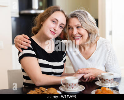 Reife Mutter und erwachsene Tochter genießen Gespräch über Tasse Kaffee zu Hause Stockfoto