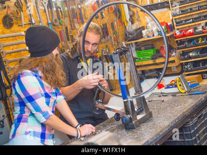 Stattliche beraded Kerl und das hübsche Mädchen Fahrrad Reparatur in der Werkstatt zusammen Stockfoto