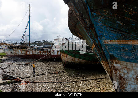 Jungen stehen unter einem Wrack eines alten Fischerbootes, Schiff Friedhof, Camaret-sur-Mer, Département Finistère, Bretagne, Frankreich, Europa Stockfoto