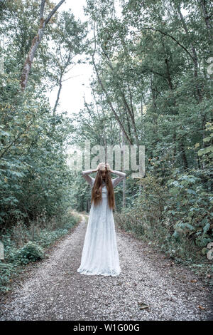 Düstere Stimmung Porträt einer Frau beim Stehen in den Wald und packte ihren Kopf mit ihren Händen. Stockfoto