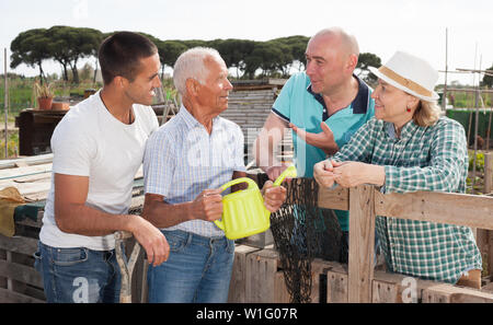 Familie von vier Gärtner zusammen gesprochen in der Nähe von hölzernen Zaun im Garten outdoor Stockfoto