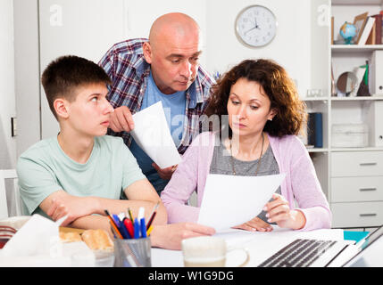 Junge Frau mit ihrem Ehemann und jugendlich Sohn Berechnung der inländischen Haushalt am Tisch Stockfoto