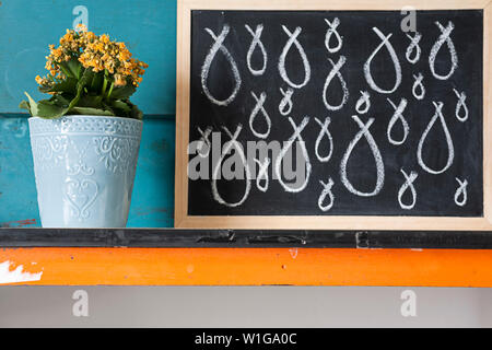 Kreative Bild von gelben Blumen im Topf mit blauen Hintergrund Mit bebilderter Beratung zur Pflege der Pflanzen mit Kreide auf einer Tafel. Stockfoto