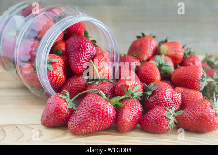 Auf die hölzerne Oberfläche des Tisches ist ein jar, aus denen reife Erdbeeren verschüttet. Stockfoto