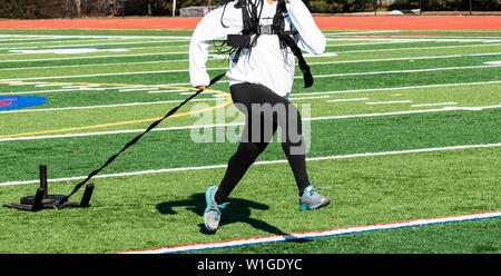 Ein High School Mädchen zieht ein Schlitten mit Gewicht während einer clod Tag tragen ein weisses Sweatshirt und schwarze Spandex. Stockfoto