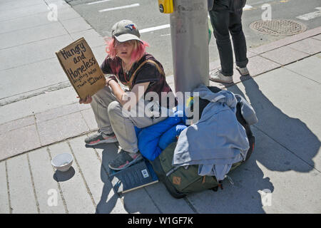 Obdachlose Mädchen mit rosa Haaren, blauen Augen im Schatten von Baseball Cap sitzt auf schlafsack an der Basis Lamp Post heraus halten erbärmliche Zeichen in der Innenstadt von Ottawa Stockfoto