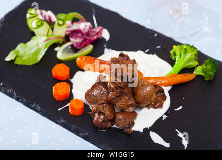 Gebratenes Huhn Leber Herz serviert mit saurer Sahne Sauce, Karotten, Brokkoli und Grüns Stockfoto