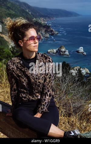 Frau im mittleren Alter von dreißiger Jahren posiert mit Schattierungen auf dem Highway 1 Cabrillo Hwy, Kalifornien, USA Stockfoto