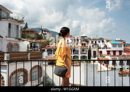 Rückansicht von Latina Mädchen mit Blick auf die malerische Stadtlandschaft der weißen Häuser. Sightseeing in Taxco, Guerrero State, Mexiko. Juni 2019 Stockfoto