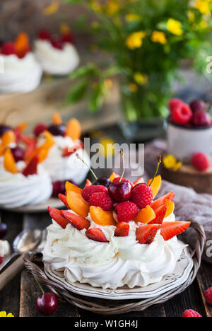 Köstliche Pavlova baiser Kuchen mit frischen Beeren auf rustikalen Hintergrund eingerichtet Stockfoto